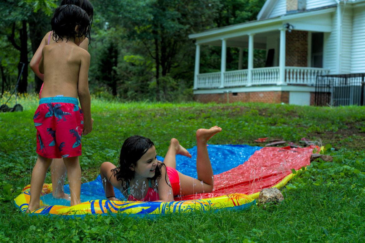 kids on a backyard water slide photographed by luxagraf
