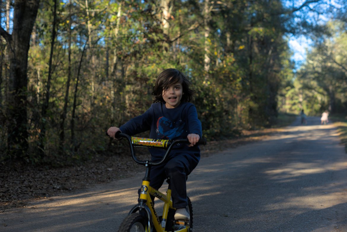 boy on a bike riding down the road. photographed by luxagraf