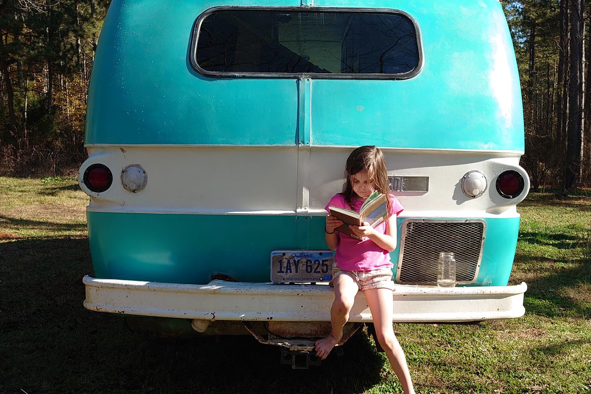 girl reading on the bumper of a dodge travco photographed by Scott Gilbertson