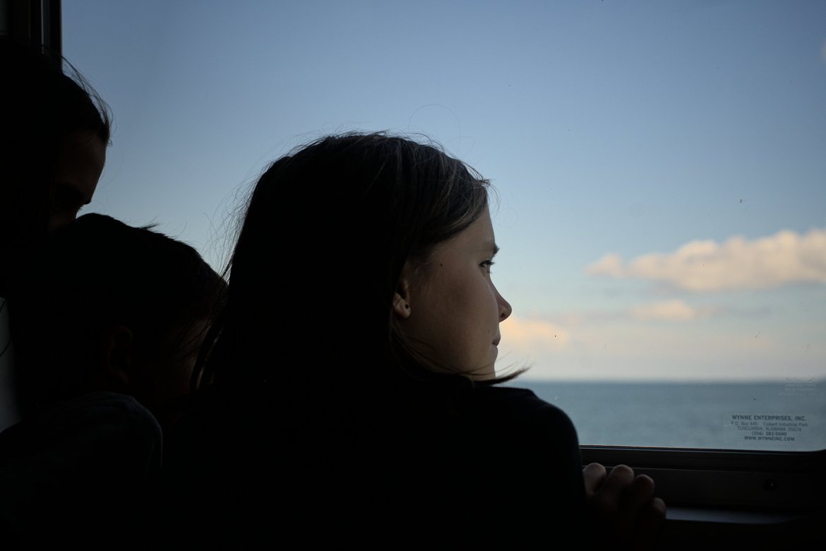girl staring out the window of the madeline island ferry photographed by luxagraf