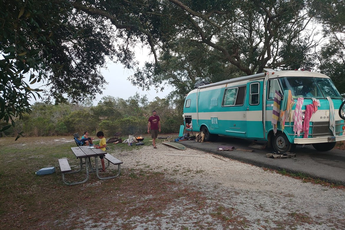 the big blue bus in a campsite covered in wet beach towels photographed by luxagraf