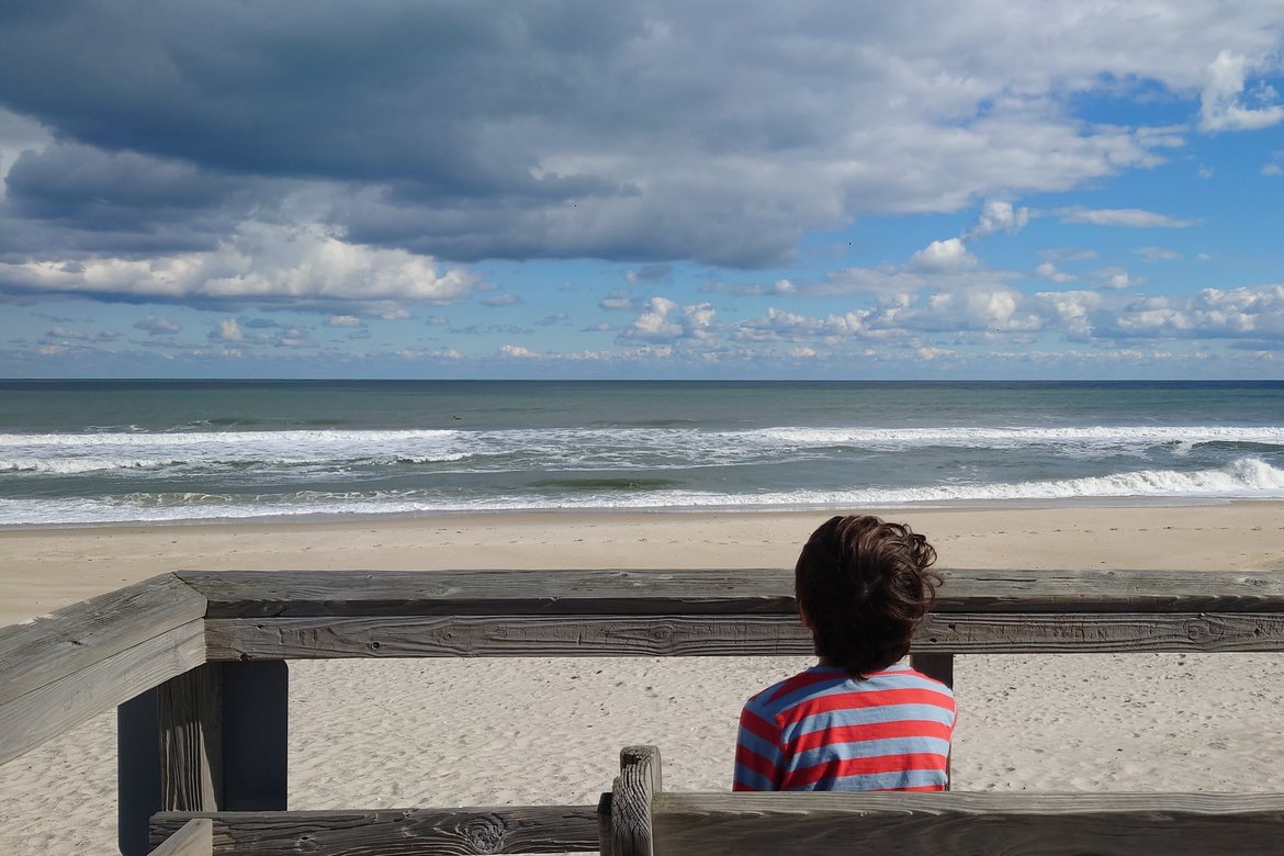 boy sitting, staring out at the sea photographed by luxagraf