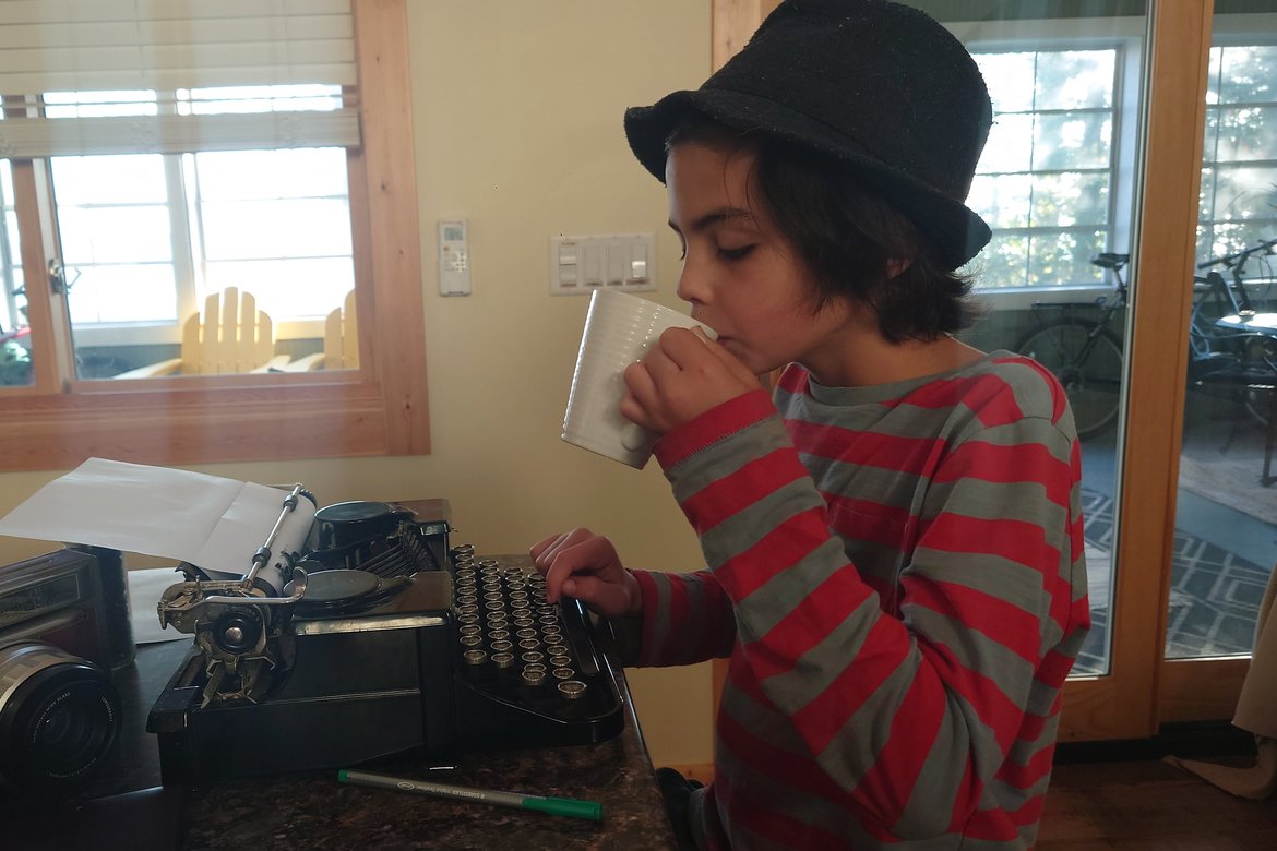 boy drinking tea while using typewriter photographed by Scott Gilbertson