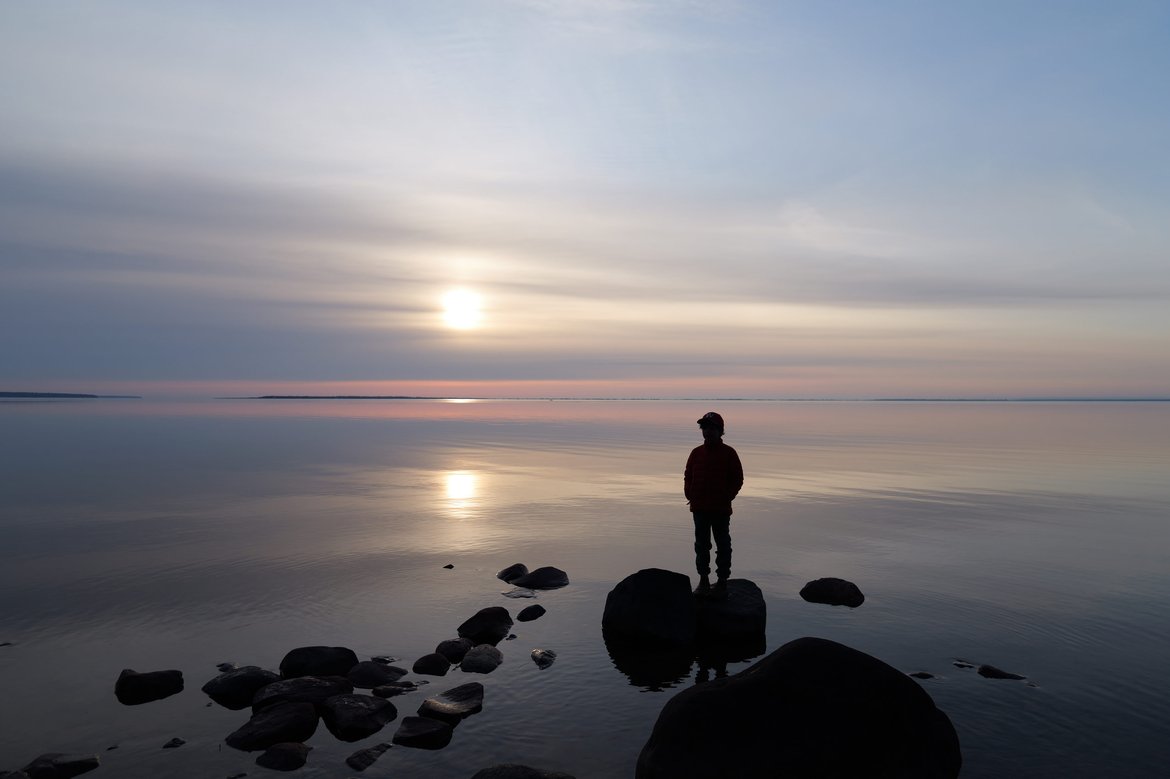 boy standing on shore looking out at the rising sun photographed by Scott Gilbertson